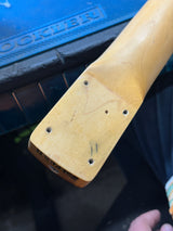 Close-up of a wooden oar handle with visible wear on a blue background