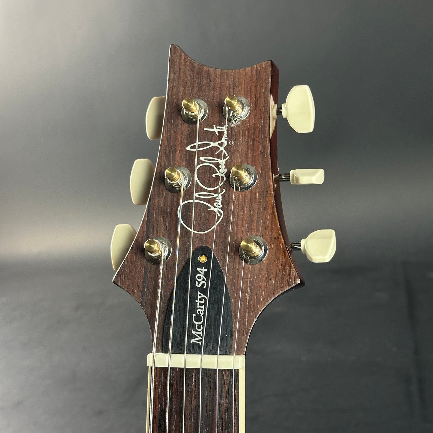 Guitar headstock with brand name on a gray background