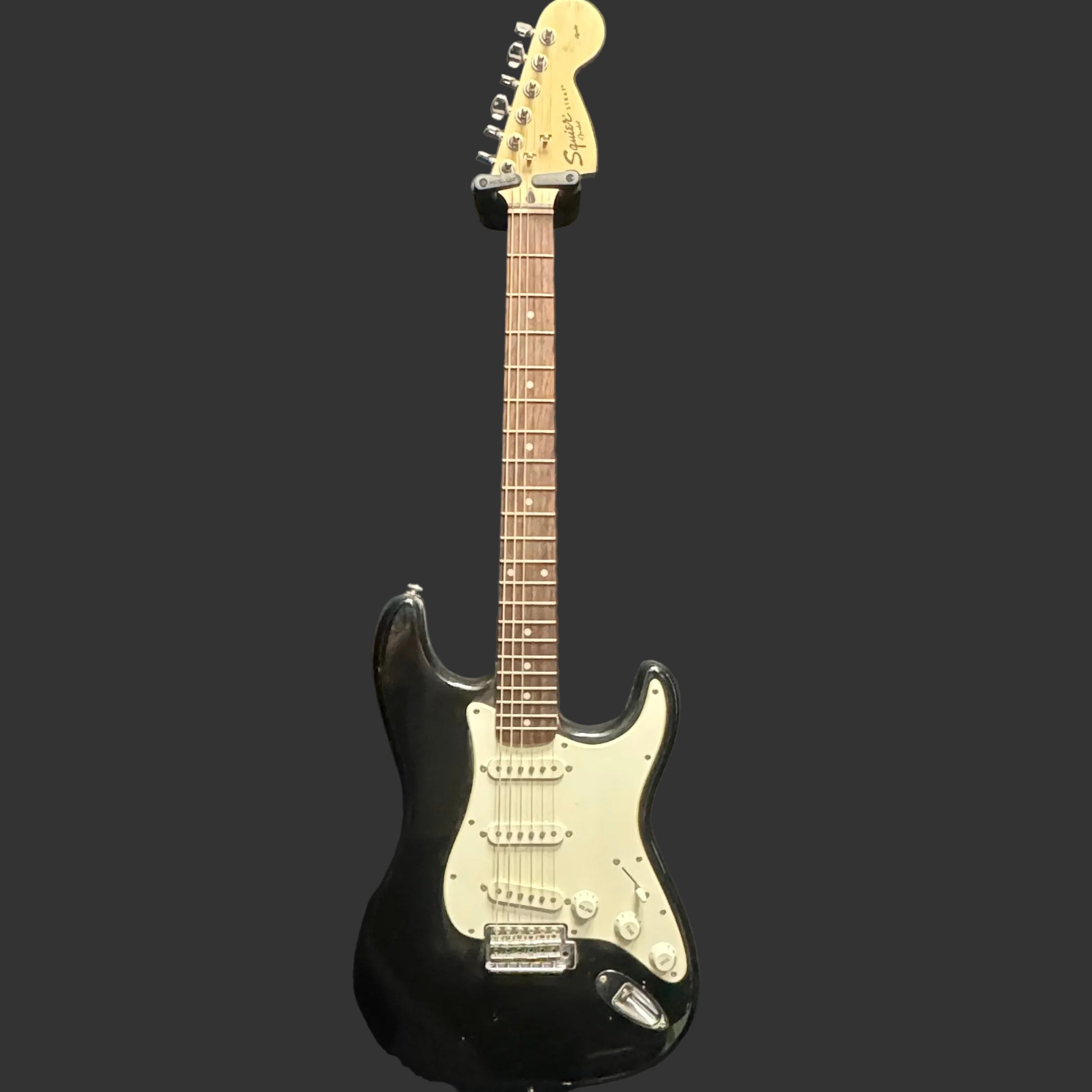 Black electric guitar with a white pickguard on a dark background