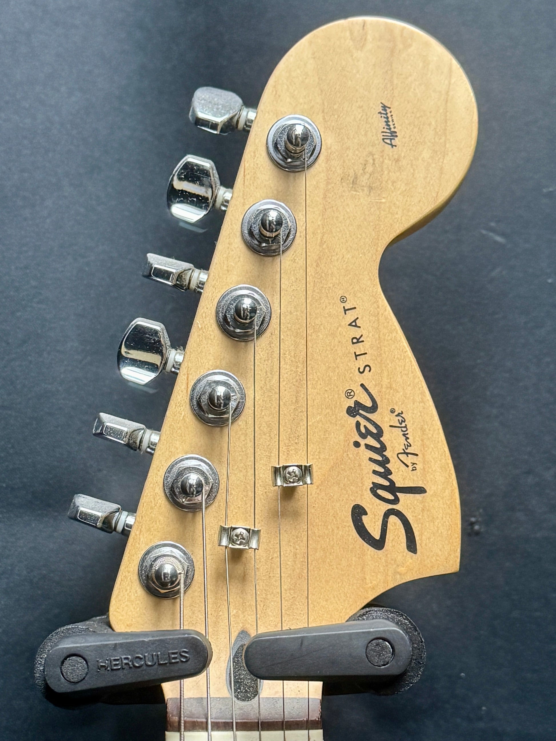 Guitar headstock with 'Squier' branding on a dark background