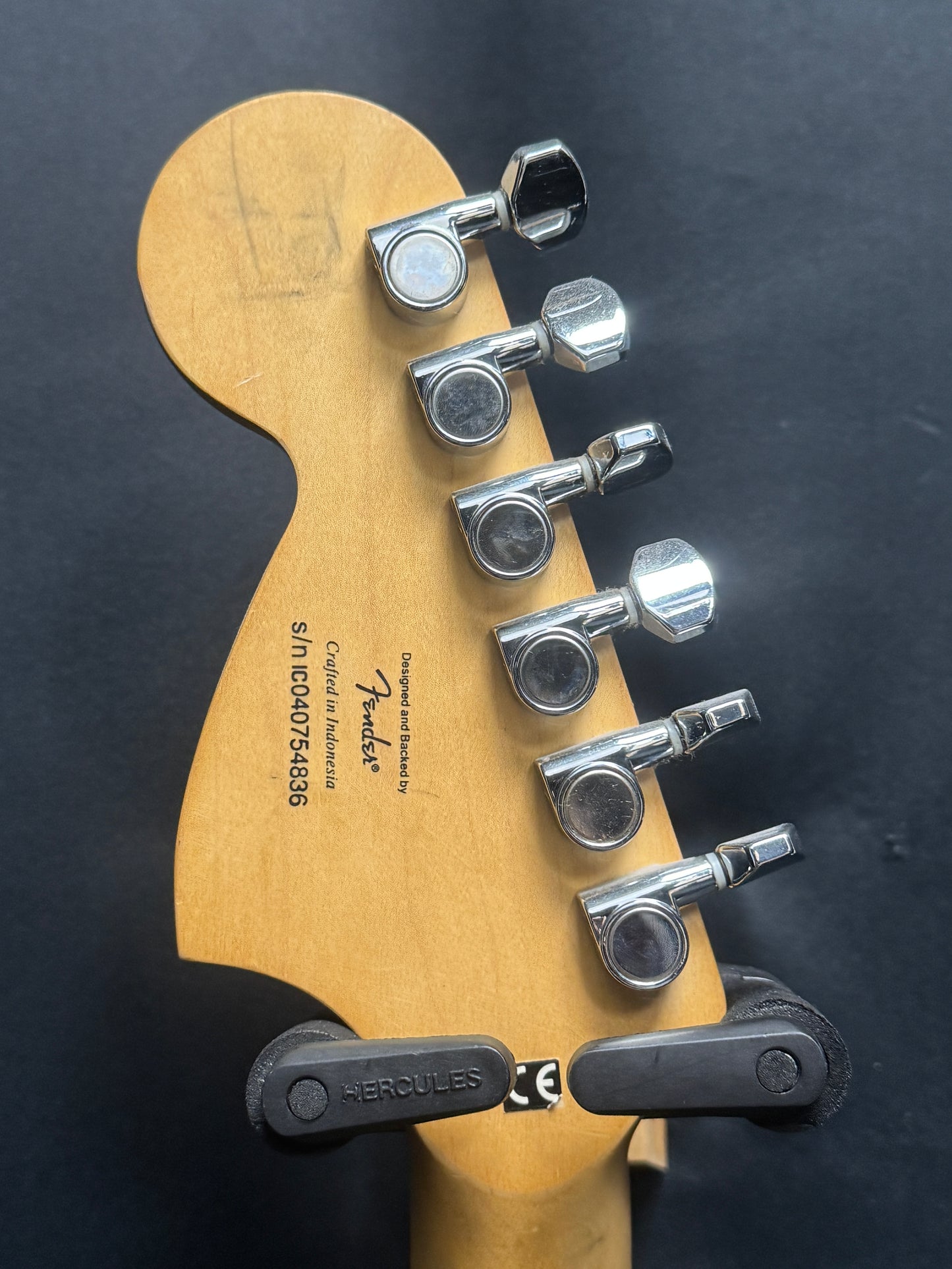 Close-up of a guitar's tuning pegs with Fender branding on a dark background