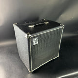 Black guitar amplifier with a brand logo on a gray background