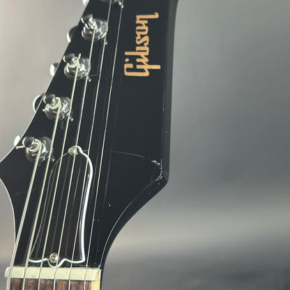 Gibson guitar headstock with brand name on a gray background