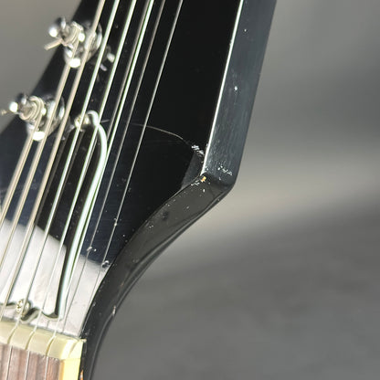 Close-up of a guitar's headstock and tuning pegs on a gray background