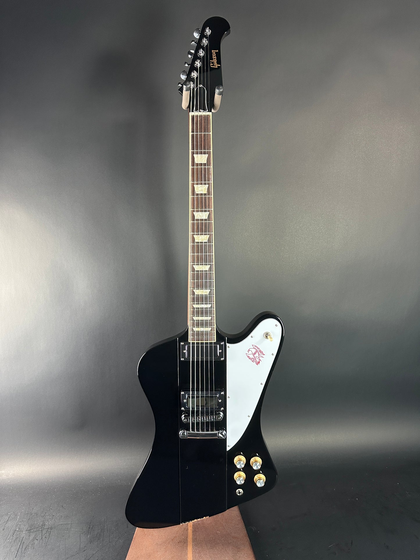 Black electric guitar with a white pickguard on a gray background