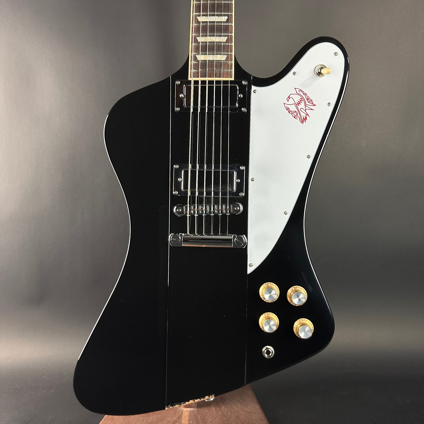 Black and white electric guitar with a logo on a gray background