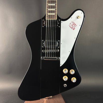 Black and white electric guitar with a logo on a gray background