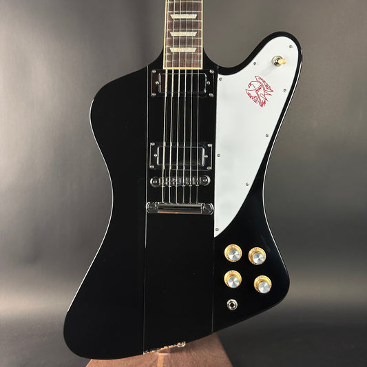 Black and white electric guitar with a logo on a gray background