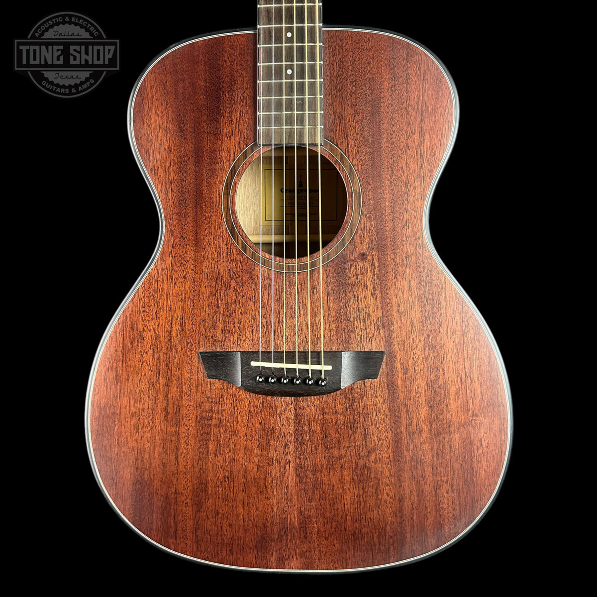 A close-up studio shot of an acoustic guitar's wooden body against a solid black background, with a Tone Shop watermark in the top-left corner.