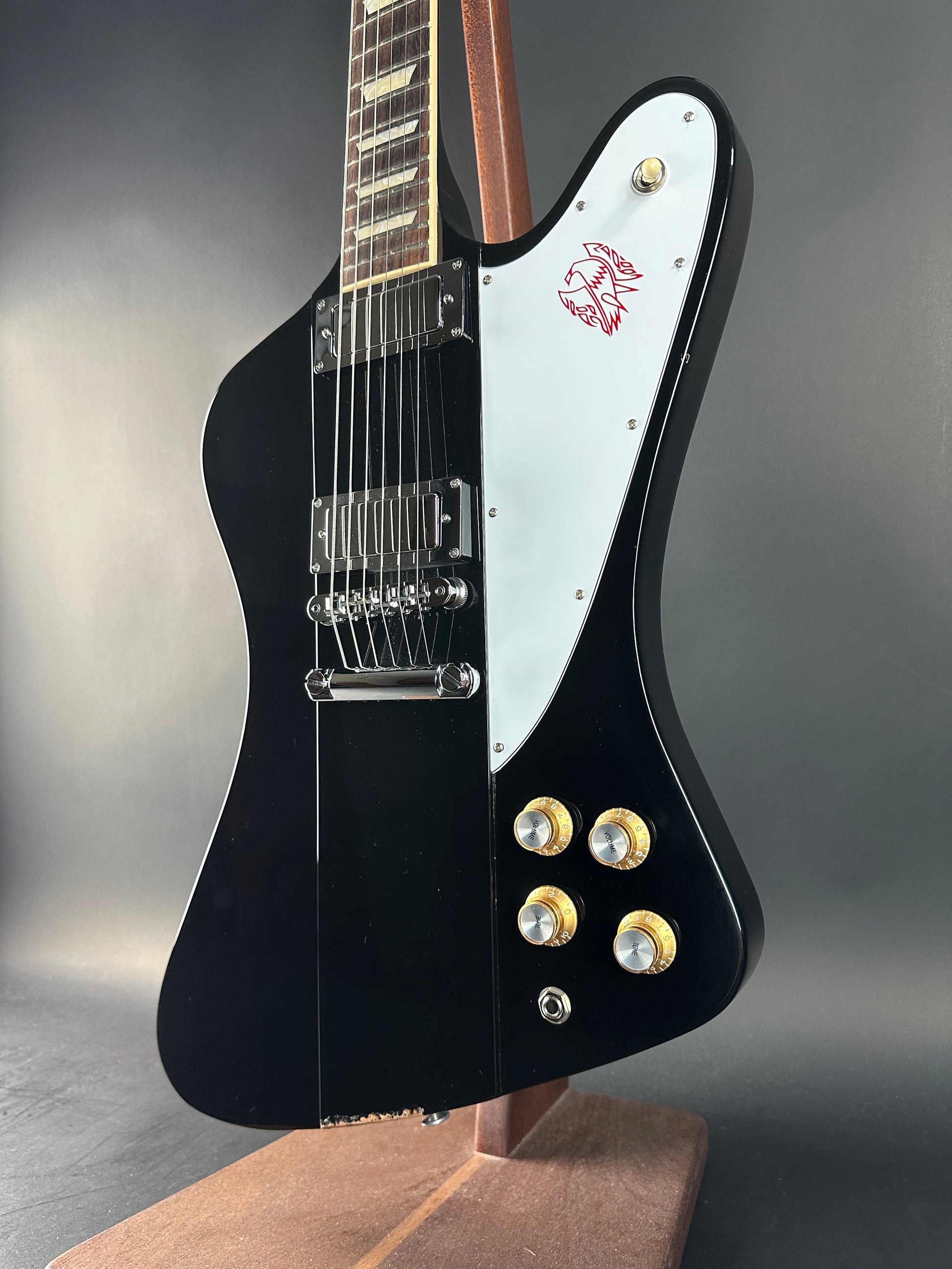 Black electric guitar with white pickguard on a gray background