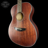 An acoustic guitar with a rich reddish-brown wood finish, shown from a three-quarters angle against a solid black background. A 'TONE SHOP' watermark is visible in the top-left corner.