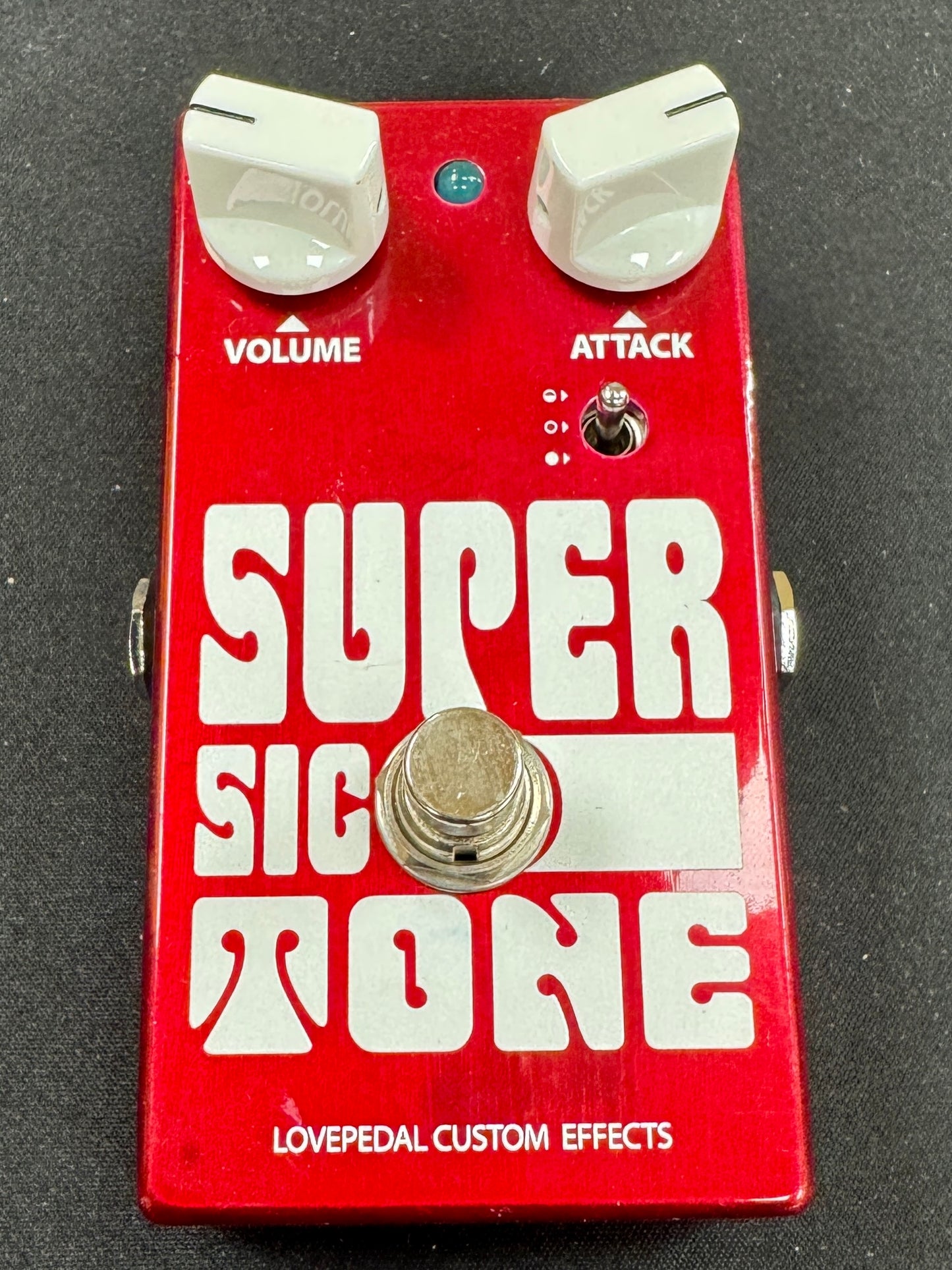 Red guitar effects pedal with 'Super Sic Tone' branding on a black background