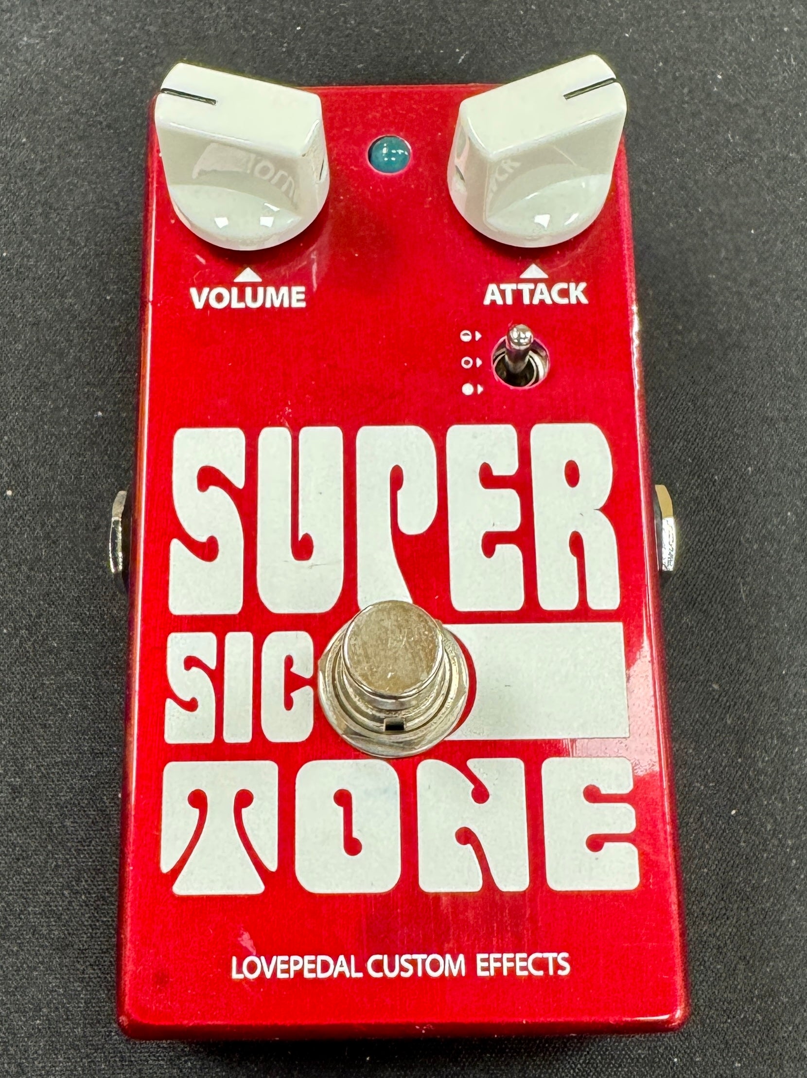 Red guitar effects pedal with 'Super Sic Tone' branding on a black background