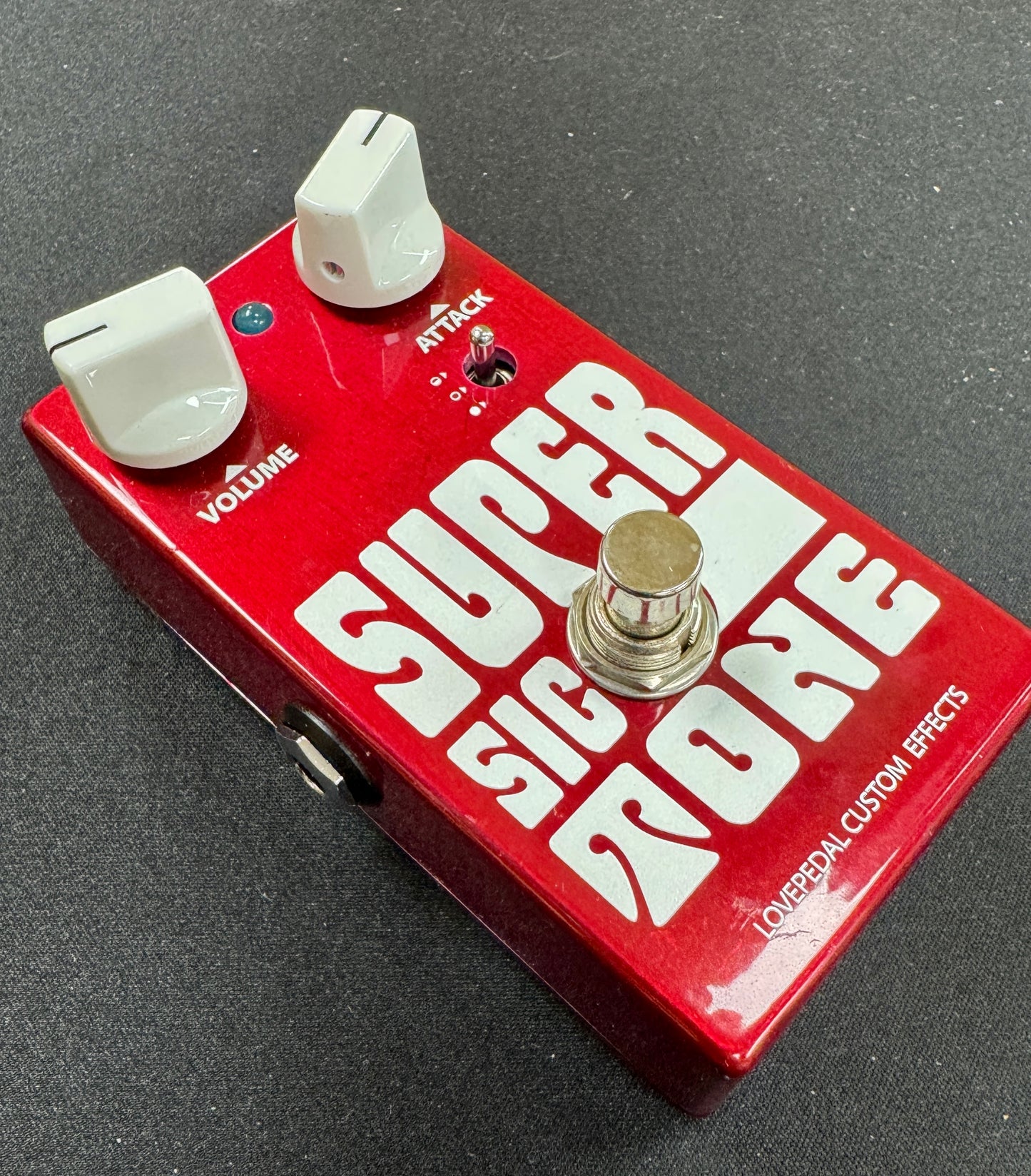 Red guitar effects pedal with 'Super Big Moe' branding on a gray background