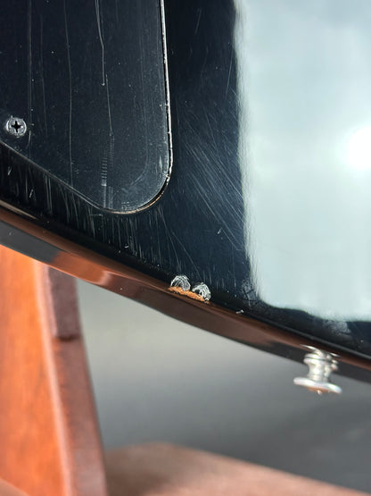 Close-up of a guitar with visible wear and screws.