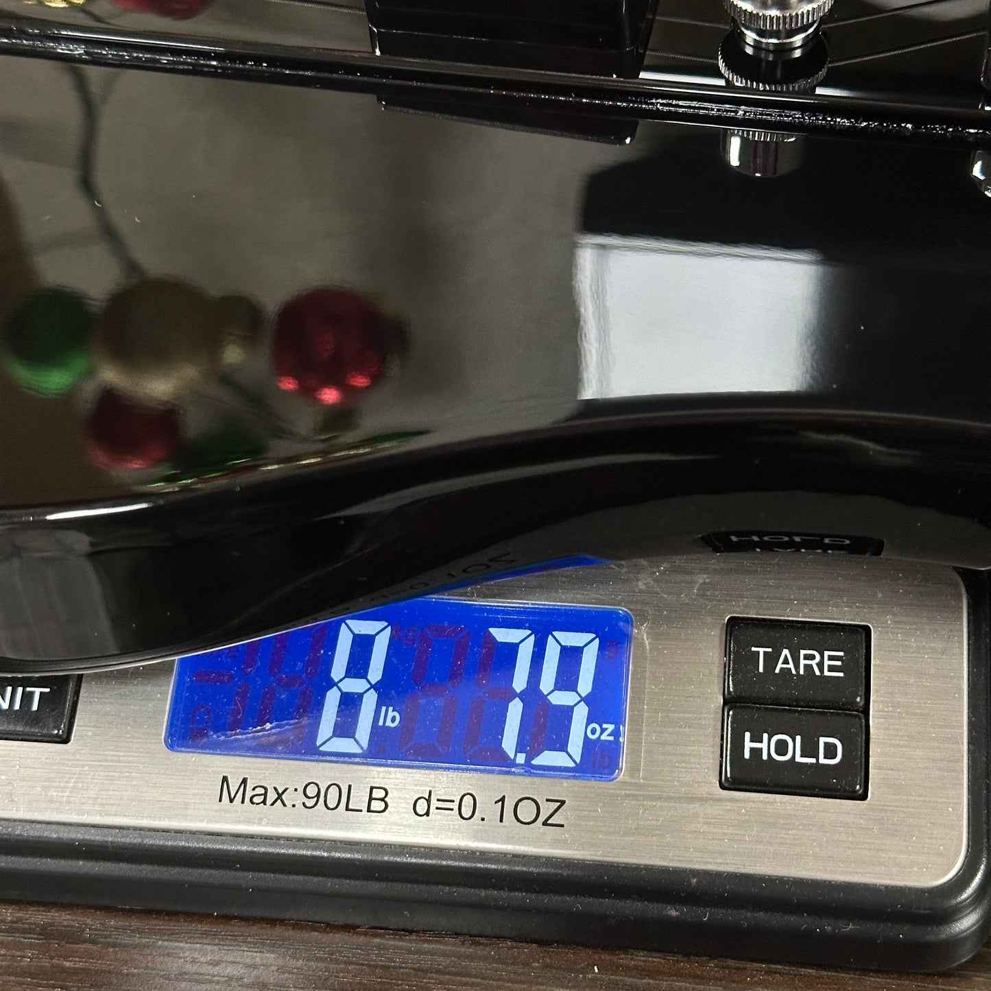 Digital scale displaying weight with buttons below on a wooden surface