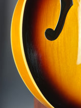 Close-up of a sunburst electric guitar body showing the glossy amber-to-brown gradient finish and a black f-hole.