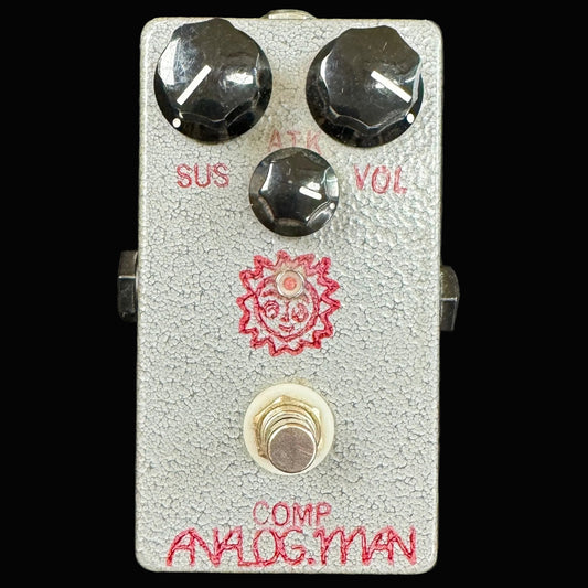 Guitar effects pedal with red text and a sun design on a gray background