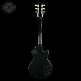 A black electric guitar shown from the back against a solid black background, with a Tone Shop watermark in the upper left corner.
