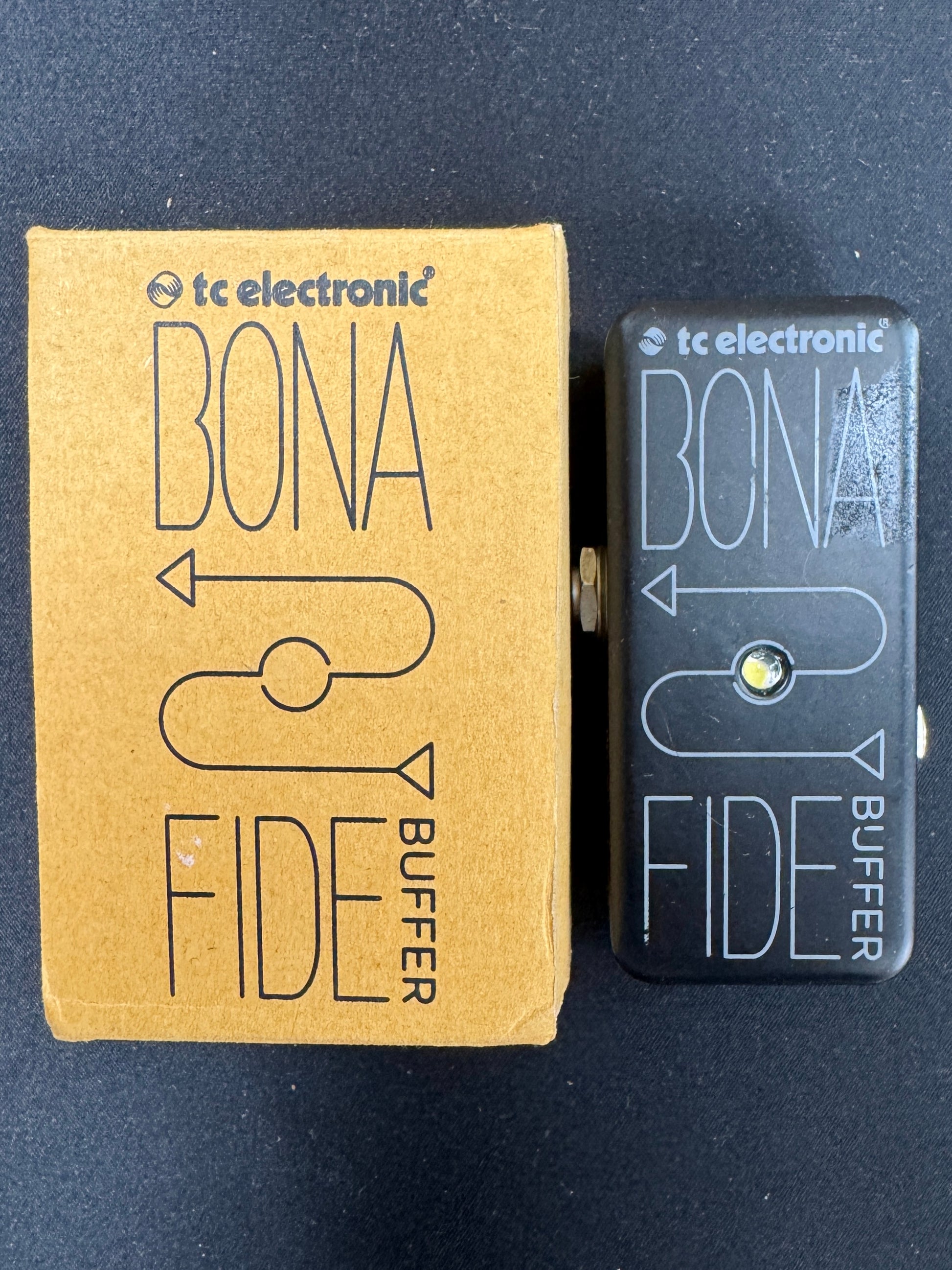 TC Electronic Bona Fide buffer pedal next to its packaging on a dark background