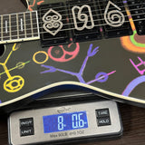 Guitar with colorful designs on the body, weighed using a digital scale.