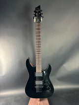 Black electric guitar on a reflective gray surface