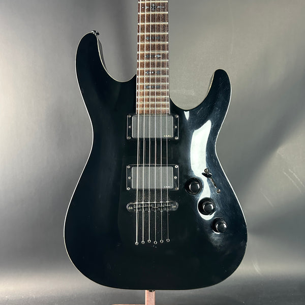 Black electric guitar on a stand against a gray background