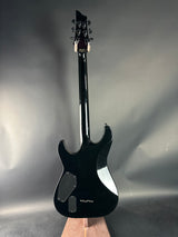 Black electric guitar on a reflective surface with a neutral background