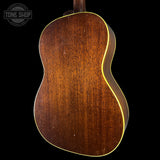 The back of a vintage acoustic guitar with a rich brown wood finish and a thin light-colored binding edge, shown against a solid black background with a Tone Shop watermark in the top left.