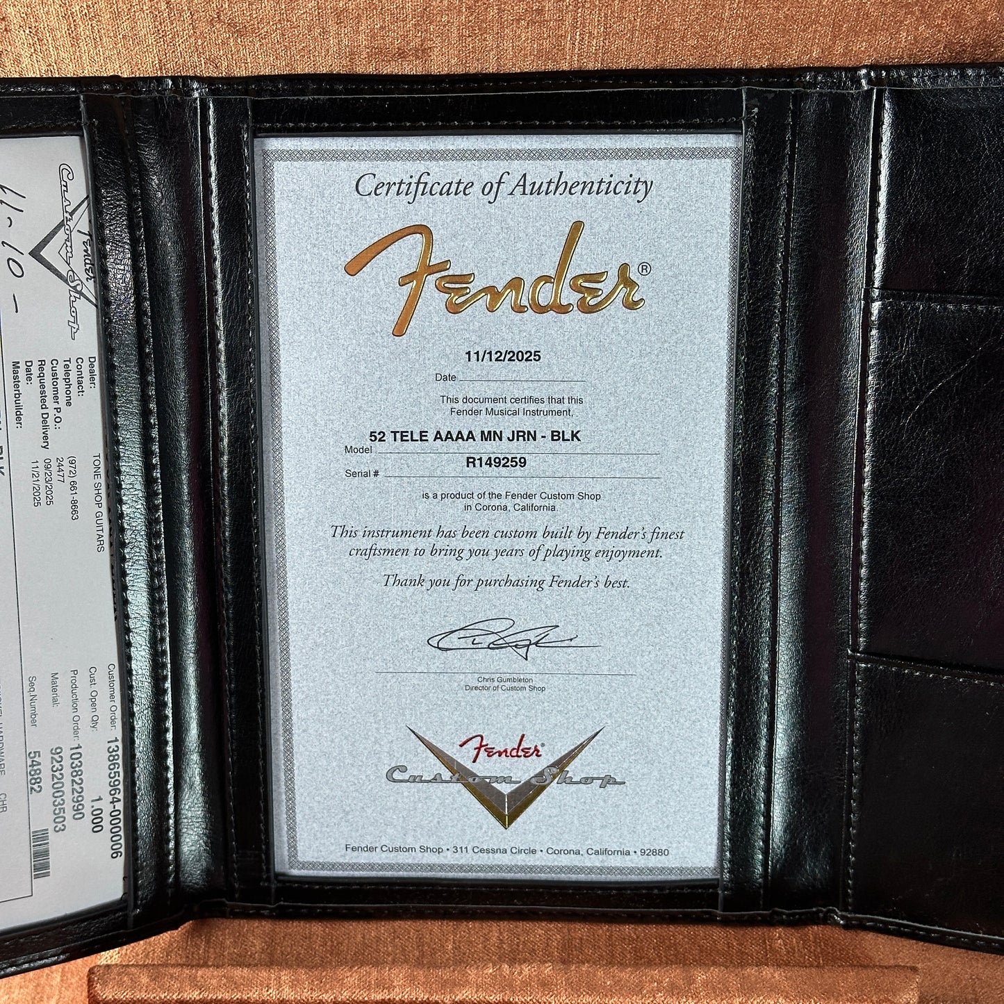 Fender certificate of authenticity in a black leather case on a wooden surface