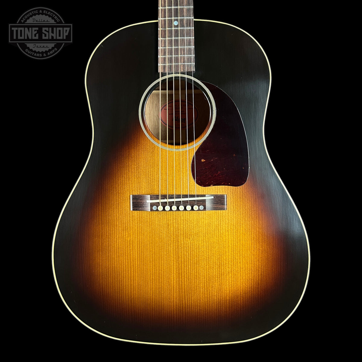 Acoustic guitar with a sunburst finish on a black background, featuring the Tone Shop logo.