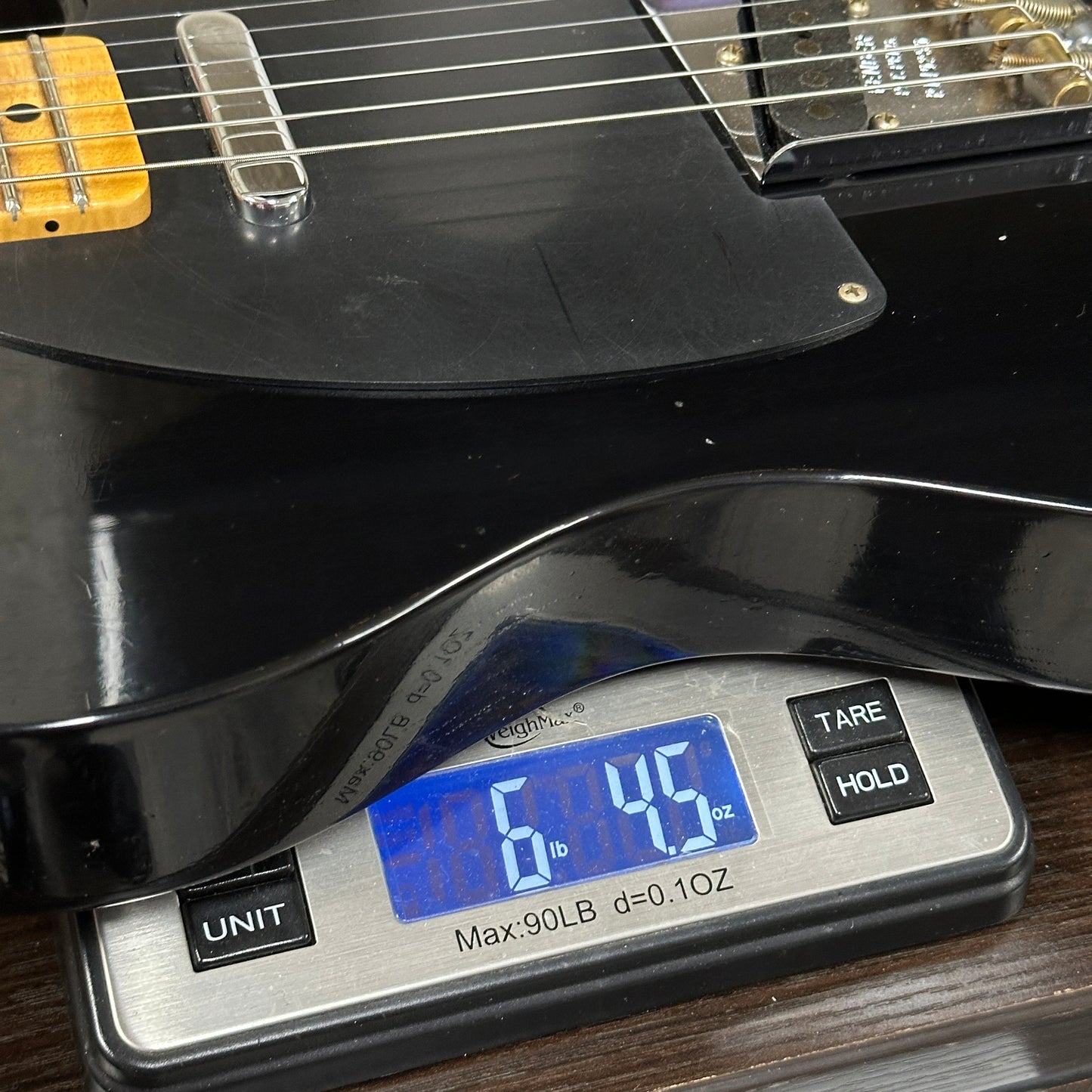 Black electric guitar on a digital scale displaying weight