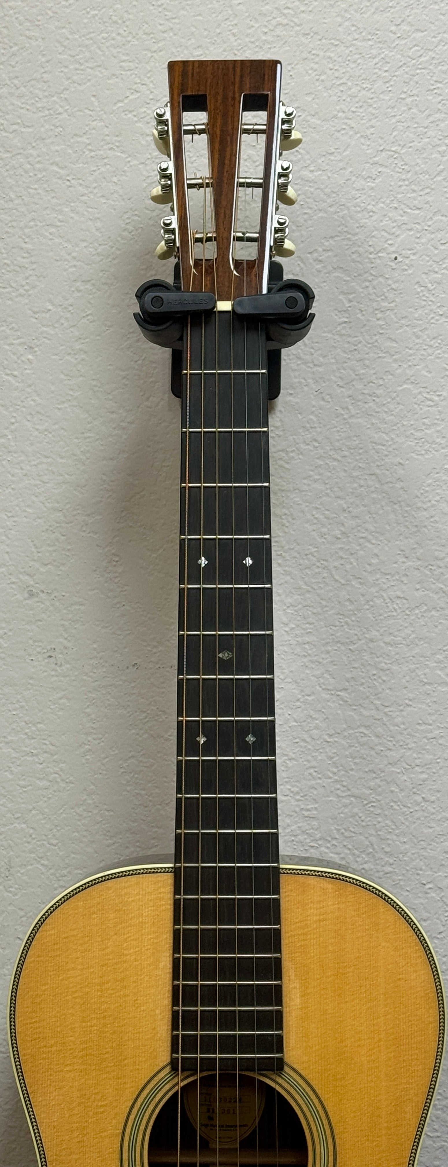 Acoustic guitar leaning against a light gray wall