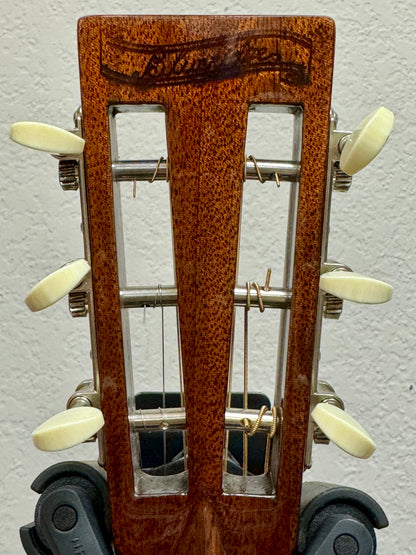 Close-up of a guitar's headstock with tuning pegs on a gray background