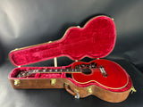 Red acoustic guitar in an open case on a dark background
