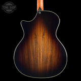 The back of an electric guitar with a glossy sunburst finish showing a warm brown wood grain, set against a solid black background with a Tone Shop watermark in the top left corner.
