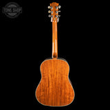 The back of an acoustic guitar with a glossy, warm brown wood finish, shown against a solid black background with a Tone Shop watermark in the top left corner.