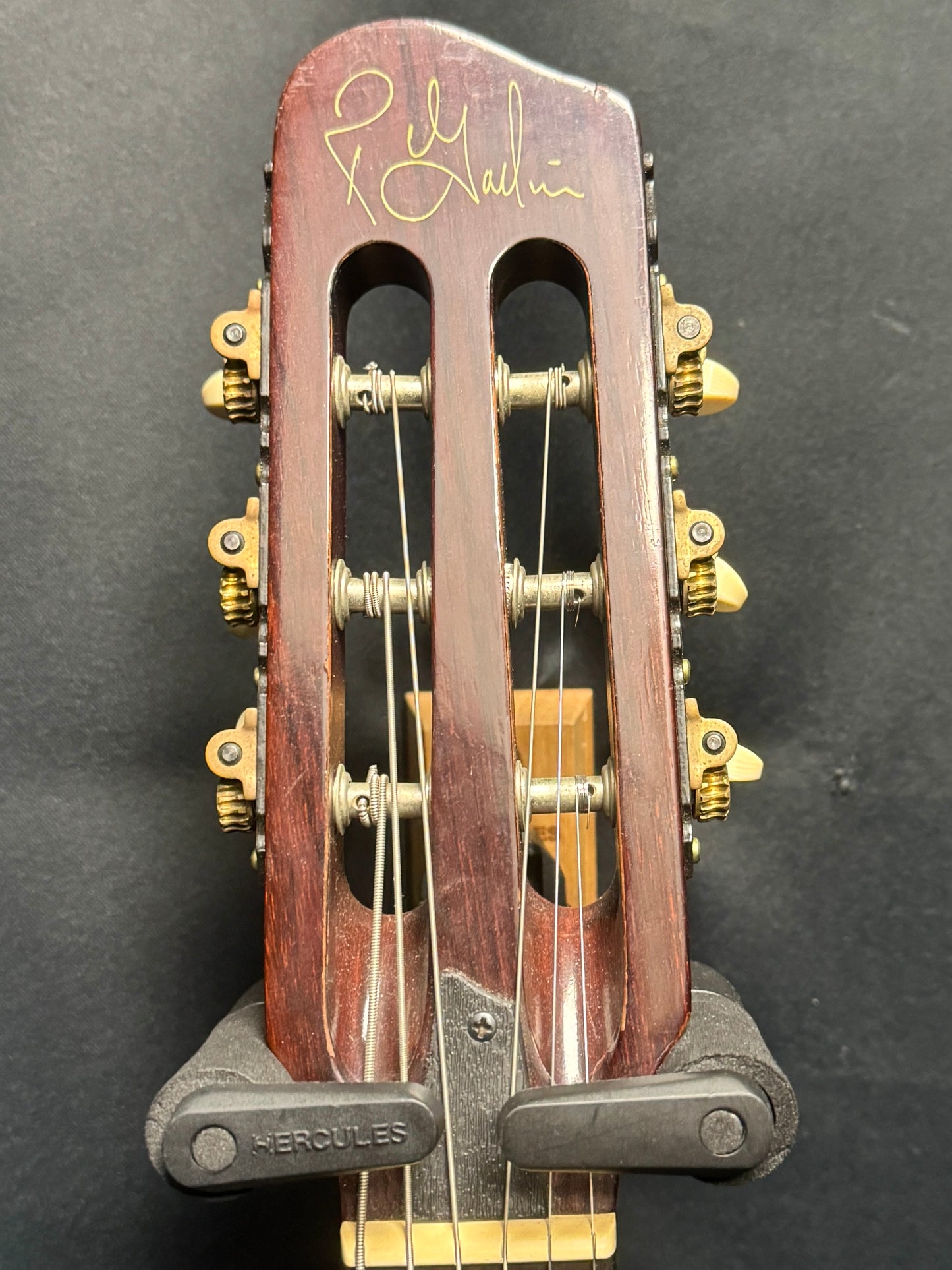 Close-up of a guitar headstock with tuning pegs on a dark background