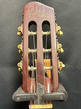 Close-up of a guitar headstock with tuning pegs on a dark background