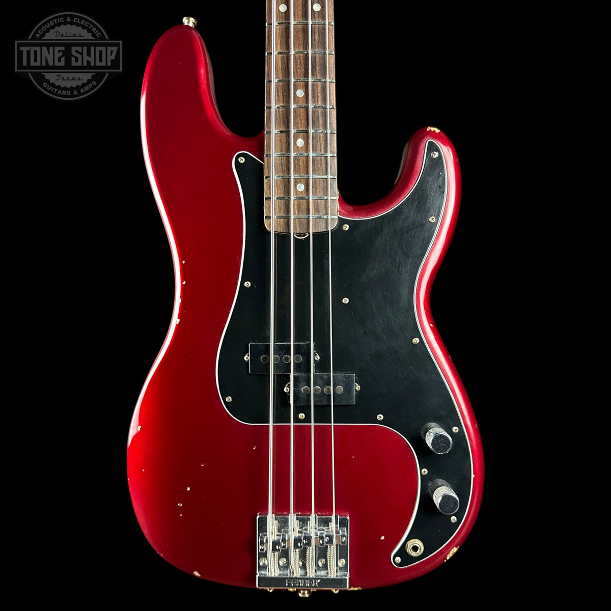 A red electric bass guitar with a black pickguard and maple neck, shown against a solid black background. A Tone Shop logo is visible in the top left corner.