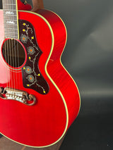 Close-up of a red acoustic guitar with decorative pickguard on a dark background