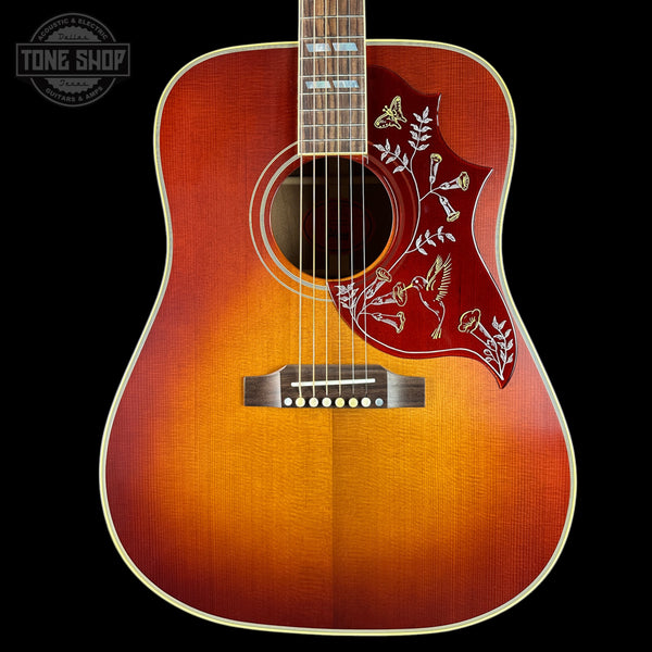 Acoustic guitar with a sunburst finish and floral design on the body, branded 'Tone Shop'.