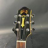 Guitar headstock with 'Guild' logo on a dark background