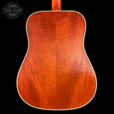 Back view of a wooden acoustic guitar with 'Tone Shop' logo.