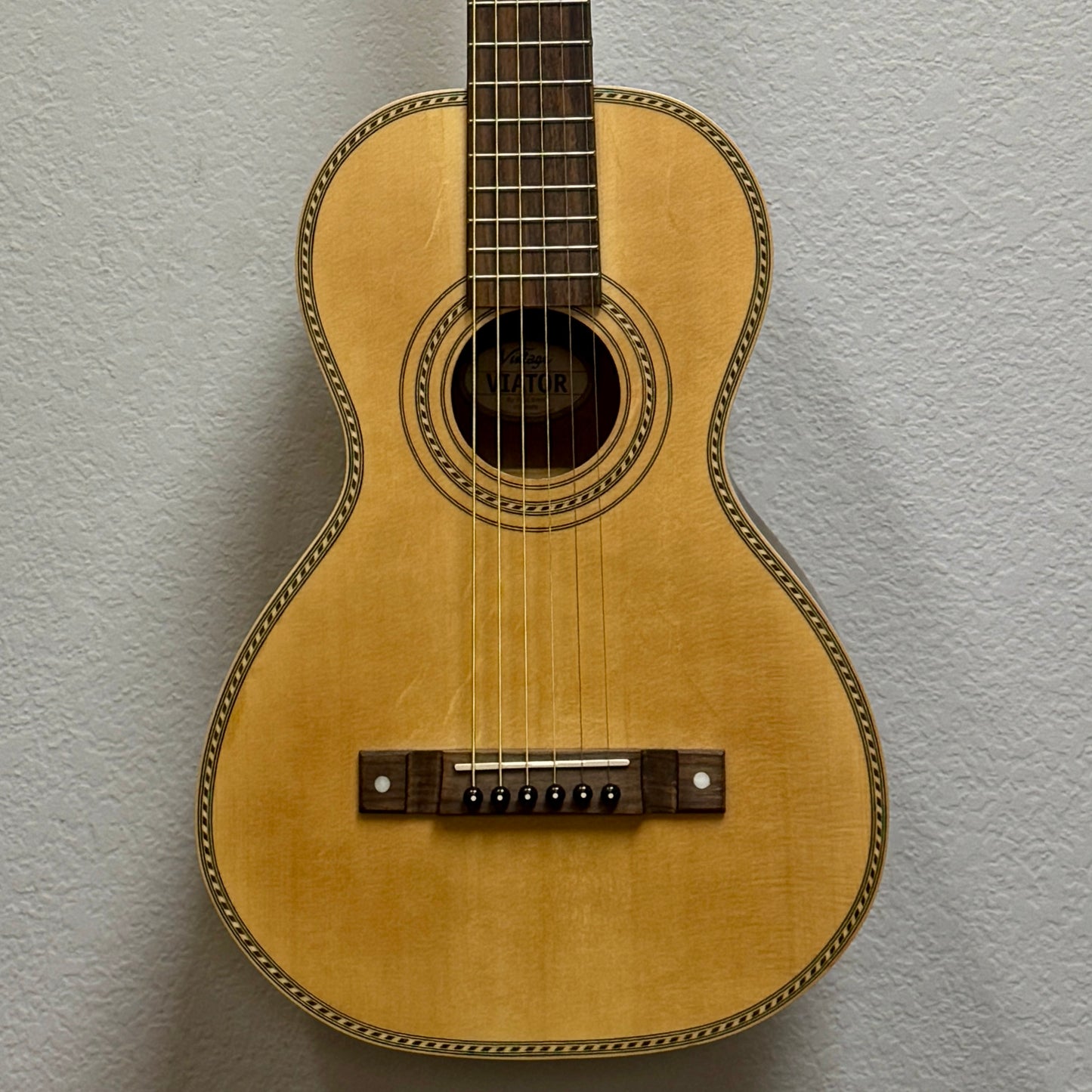 Small wooden guitar on a textured gray background