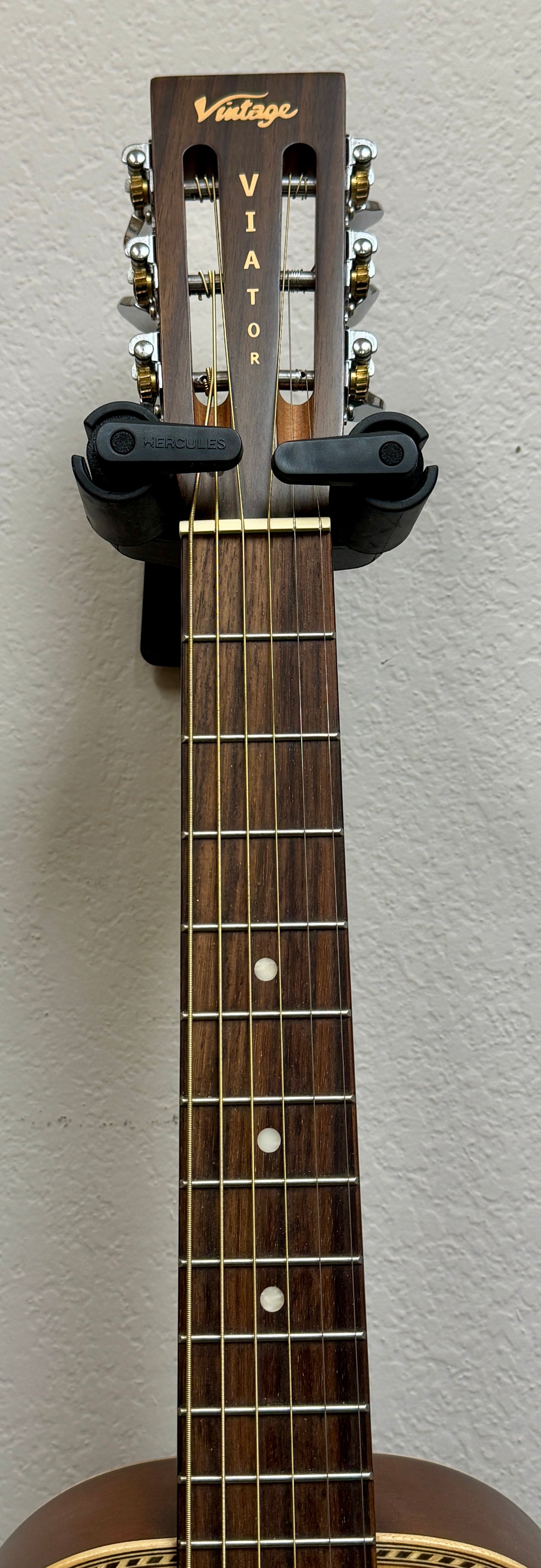 Close-up of a guitar neck with a 'Vintage' headstock on a gray background