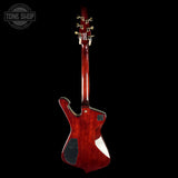 A single-cutaway electric guitar shown from the back, featuring a glossy dark red cherry finish and gold tuning pegs, set against a solid black background with a Tone Shop watermark in the top left corner.