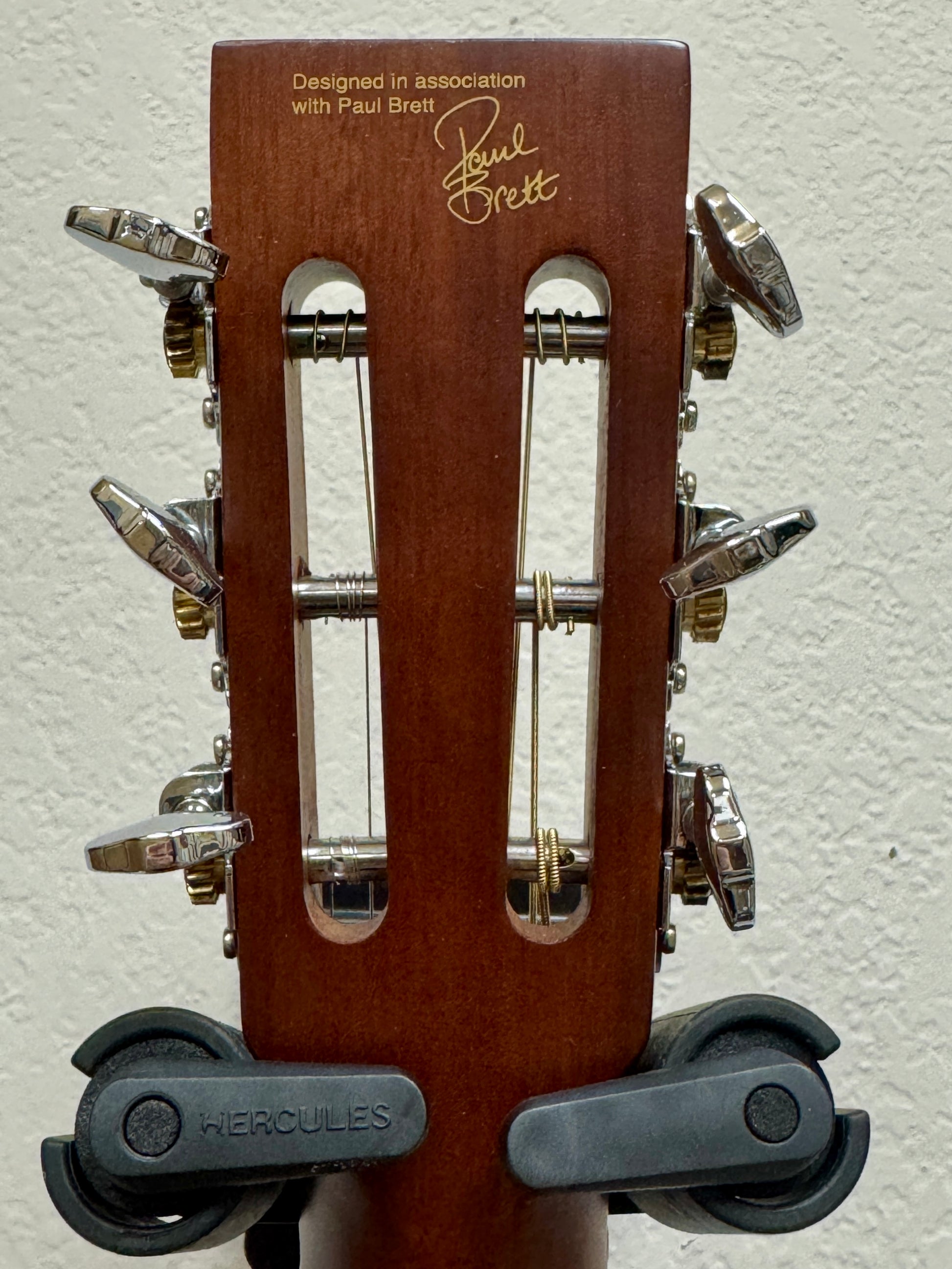 Guitar headstock with wooden finish and metal tuning pegs on a white background