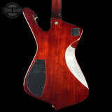 The back of a custom electric guitar body made of reddish-brown wood with a glossy finish, featuring a white curved inlay, black pickups, and gold hardware, shown against a black background with a Tone Shop watermark.