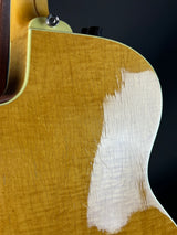 Close-up of a guitar's wooden body with a white patch on a black background
